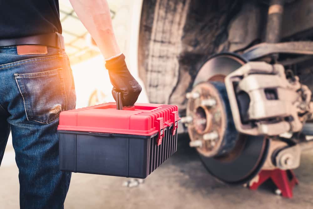 mechanic holding toolbox next to truck